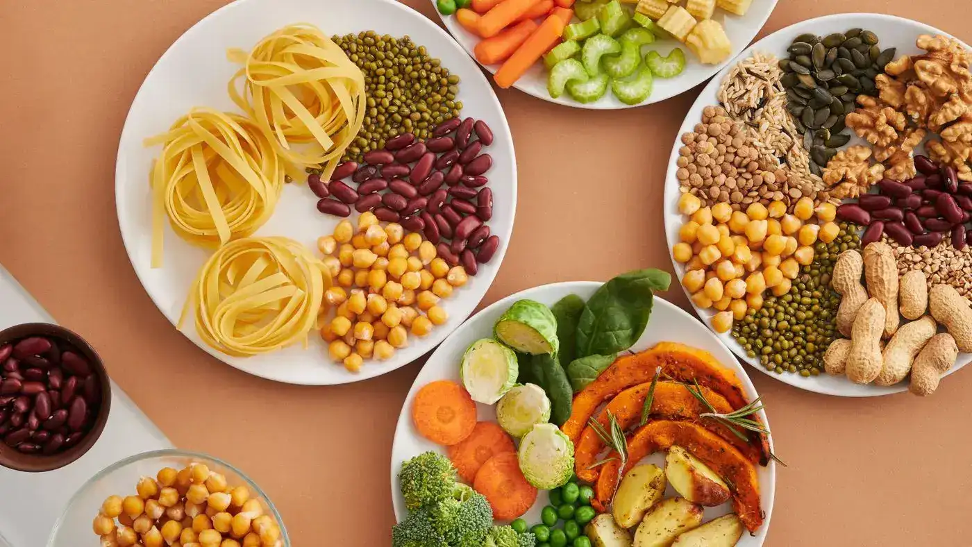 Platos vistos desde arriba con lentejas, fríjoles, garbanzos, maní, nueces, brócoli y arvejas: ejemplo de comida para la dieta DASH
