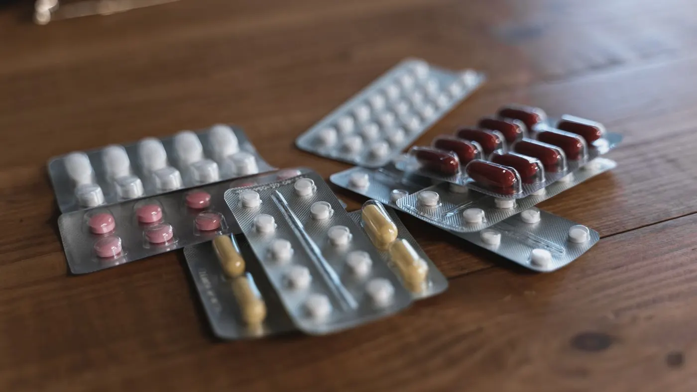 Tiras de pastillas blancas, rosadas, amarillas y rojas sobre una mesa de madera, imagen para la guía de la hidroclorotiazida