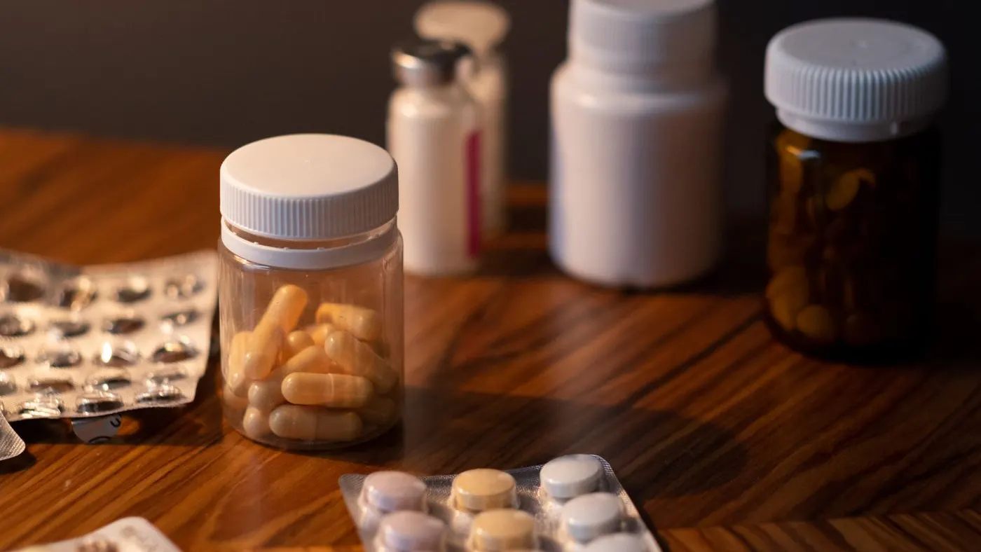 Frascos y tiras de pastillas sobre una mesa de madera, imagen para la guía de la tableta que combina losartán con hidroclorotiazida